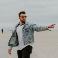 Man on beach pointing, representing media and communication services.