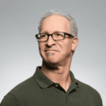 Professional man wearing glasses and a green polo shirt.