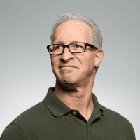 Professional man wearing glasses and a green polo shirt.